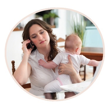 A person making a phone call while they hold a baby.