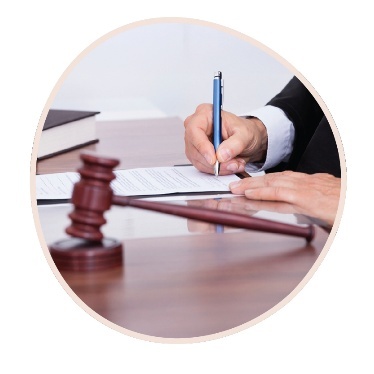 A person writing on a document next to a gavel.