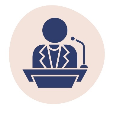 A person in a suit standing behind a podium with a microphone.